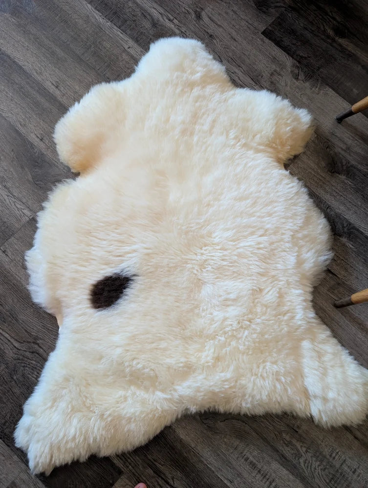 Cream-colored british isles sheepskin rug with a dark brown spot 48 x 32 inches soft and cozy isles sheepskin