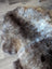 A plush british isles sheepskin rug in natural brown gray and white fur with an irregular shape measuring 47 by 31 inches
