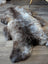 A plush british isles sheepskin rug in natural gray and brown tones with soft dense fur texture measuring 47 by 31 inches