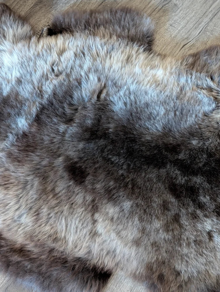 A plush british isles sheepskin faux fur rug in natural brown and gray tones with soft dense texture 47 by 31 inches