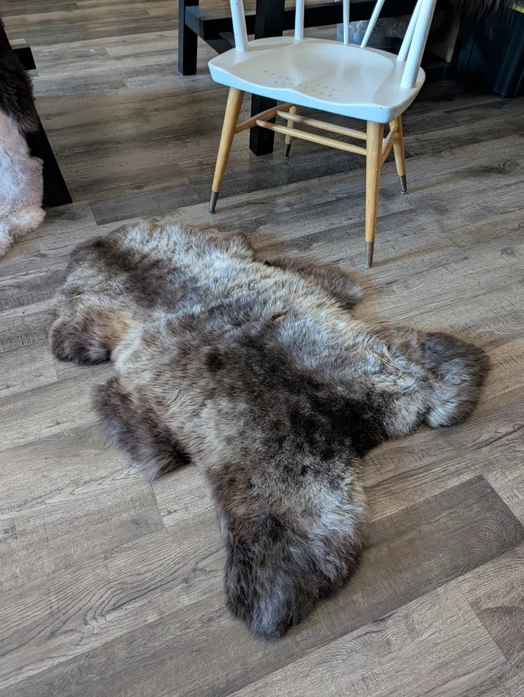 A plush natural-toned british isles sheepskin rug with soft fluffy texture and irregular edges on wooden floor