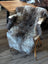 A plush natural gray and black british isles sheepskin rug draped over a wooden chair for cozy style