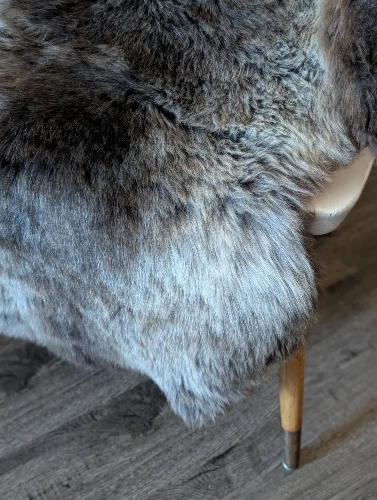 A plush gray british isles sheepskin rug with soft dense faux fur and natural shade variations 47 x 31 inches