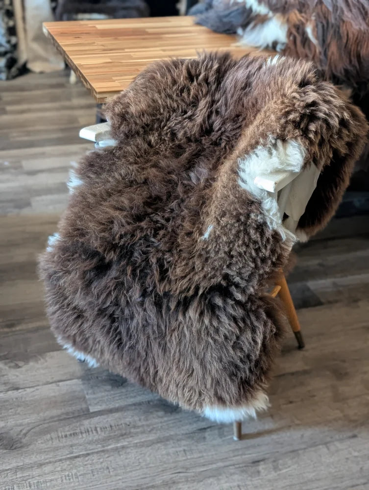 Thick fluffy brown british isles sheepskin rug with soft natural texture and white underfur trim sized 54 x 31 inches