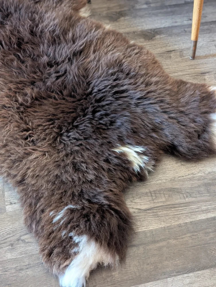 A plush natural brown british isles sheepskin rug with thick soft fur and subtle white patches on edges