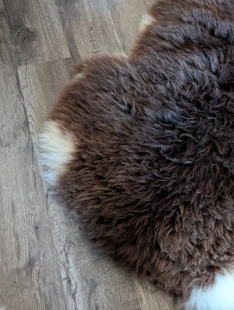 A plush thick brown british isles sheepskin rug with soft curly texture and white fur edge sized 54 by 31 inches