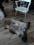 Brit16 british isles sheepskin fur rug with gray brown tones in an irregular shape on a wooden floor