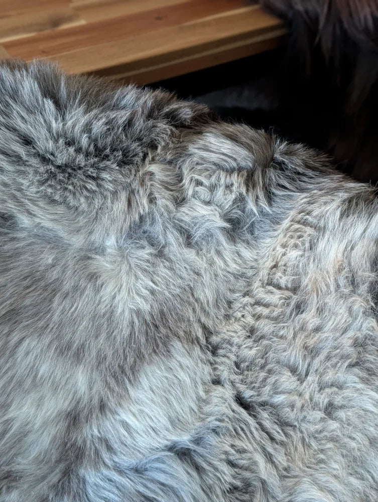A plush grayish-brown british isles sheepskin rug with thick natural fur texture sized 47 by 29 inches