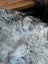 A plush grayish-brown british isles sheepskin rug with thick natural fur texture sized 47 by 29 inches