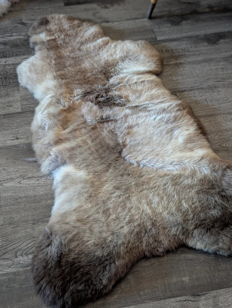 A plush natural-toned british isles sheepskin rug with soft dense fur and irregular edges sized 49 by 22 inches