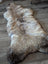 A plush natural-toned british isles sheepskin rug with soft dense fur and irregular edges sized 49 by 22 inches