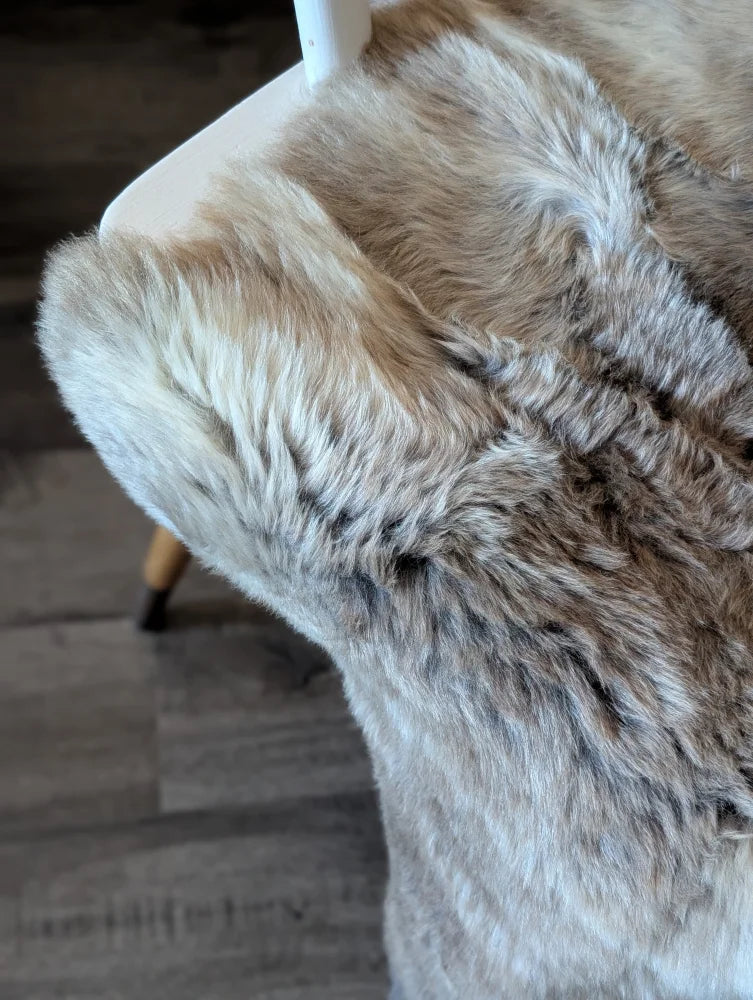A plush natural-toned british isles sheepskin throw with soft dense faux fur in beige and gray hues measuring 49 x 22 inches