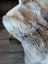 A plush natural-toned british isles sheepskin throw with soft dense faux fur in beige and gray hues measuring 49 x 22 inches