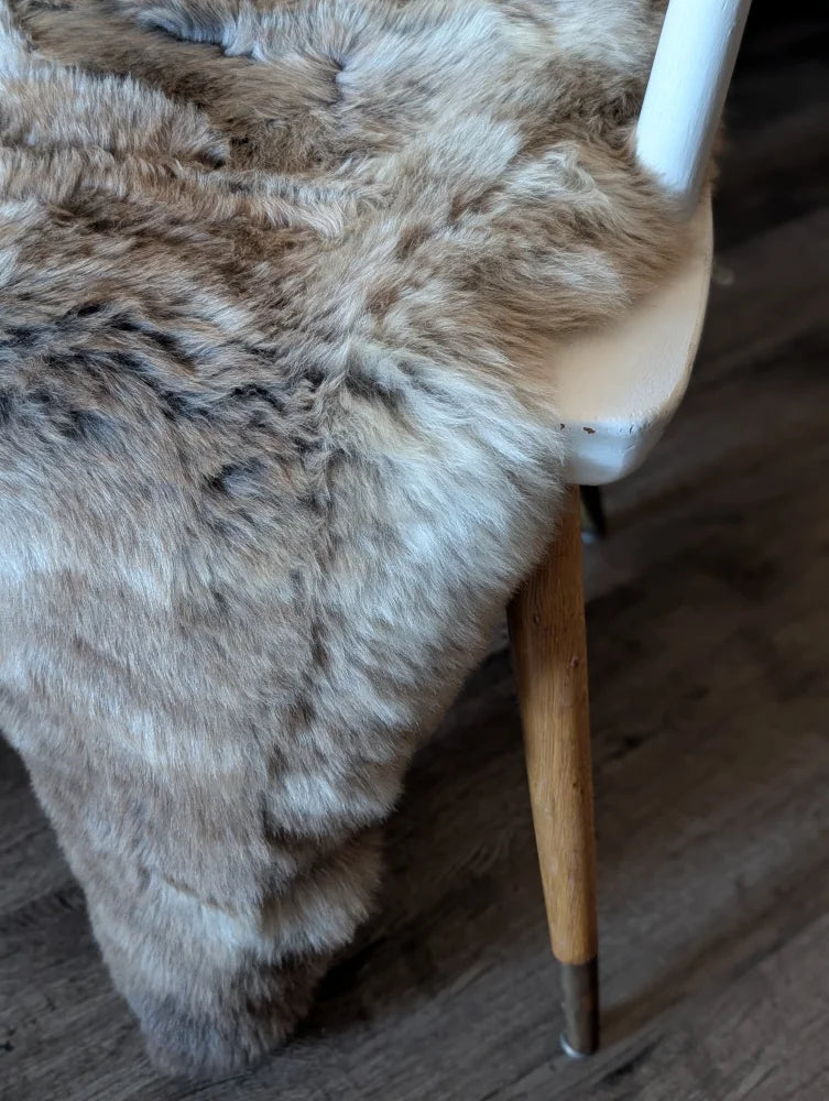 A plush british isles sheepskin throw in natural brown and gray tones with soft dense faux fur texture