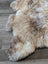 A natural-toned british isles sheepskin rug with soft fluffy texture and irregular edges in 48 by 33 inches