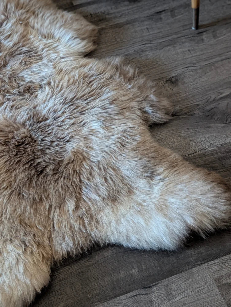 A natural-toned british isles sheepskin rug with soft fluffy texture and irregular edges measuring 48 x 33 inches