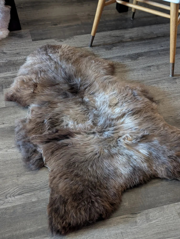 A plush natural brown and gray british isles sheepskin rug with thick soft fur texture measuring 49 by 29 inches