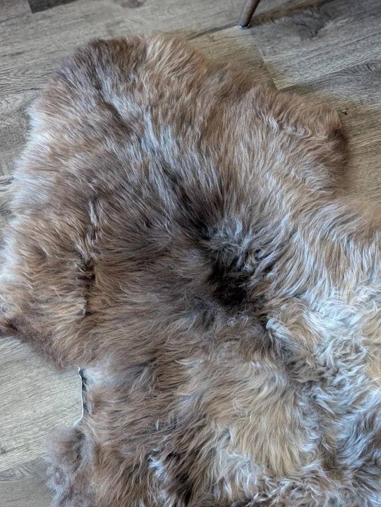 A plush british isles sheepskin rug 49 by 29 inches with warm brown and gray tones and natural texture