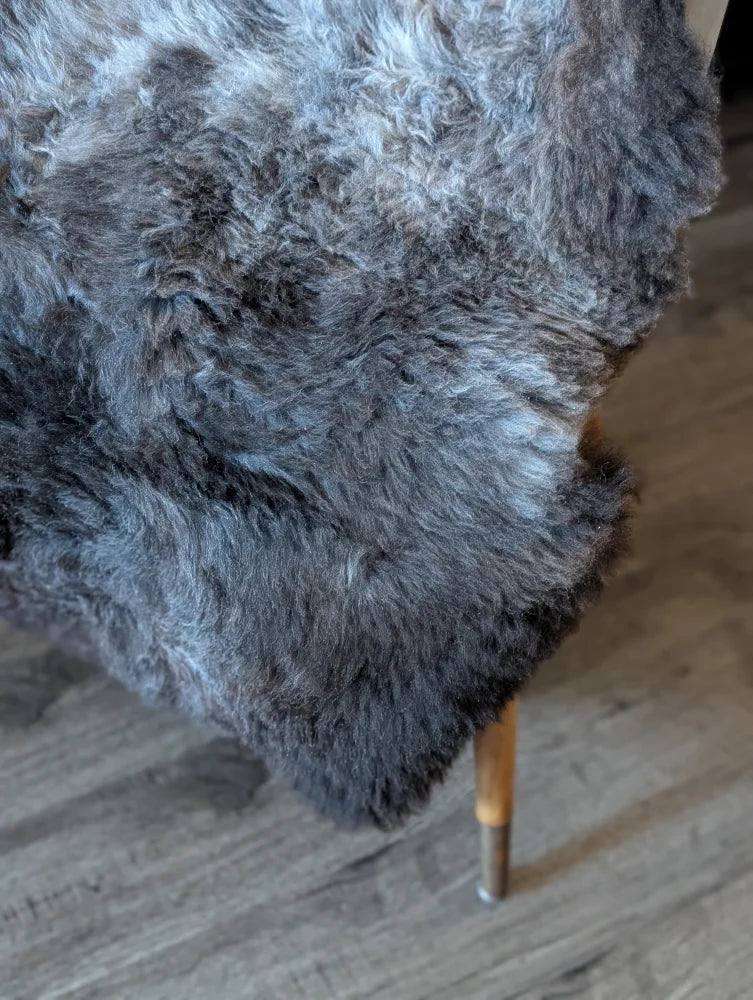 A plush dark gray british isles sheepskin rug with soft curly texture measuring 47 x 31 inches