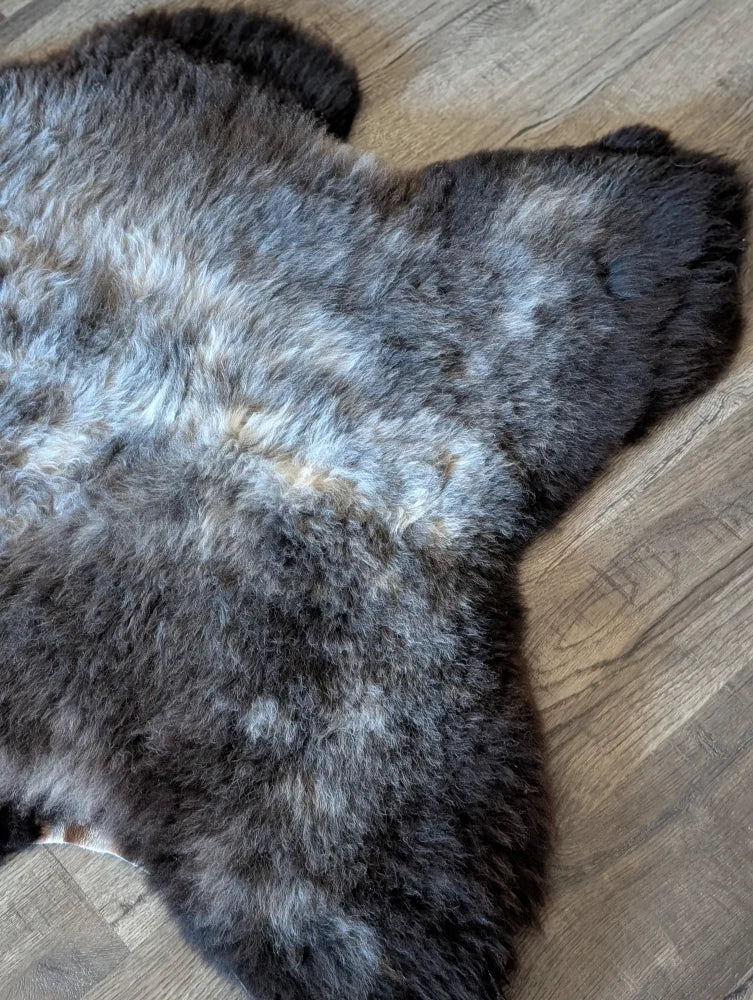 A plush gray and black british isles sheepskin rug with natural texture and soft fluffy appearance sized 47 by 31 inches