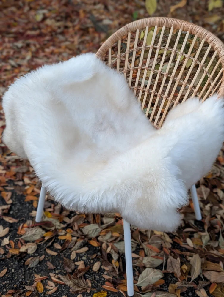White faux fur chair cover draped over wicker chair made from very soft british isles sheepskin