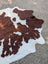 Large brown and white angus oliver cowhide rug with natural longer haired fur texture adding rustic charm