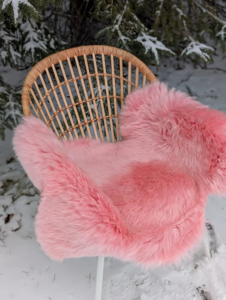 Pink merino sheepskin faux fur chair cover draped over wicker chair arriving mid october