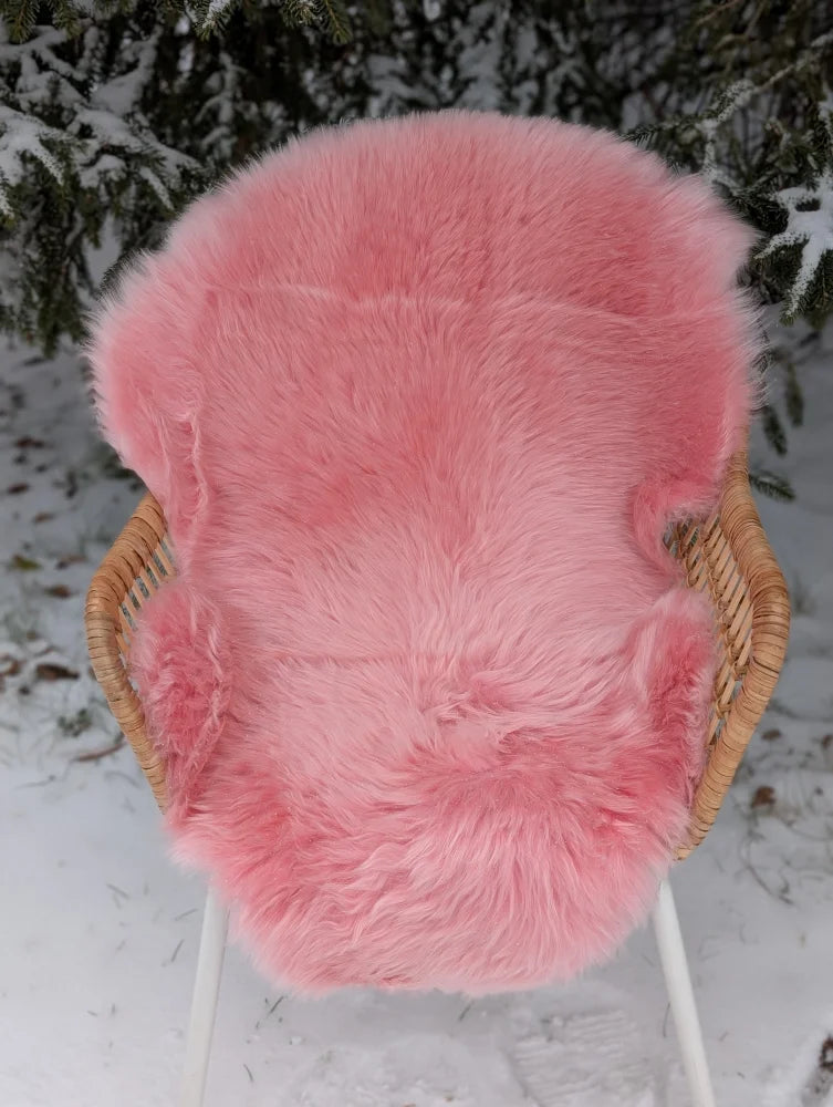 Bubblegum pink merino sheepskin chair cover draped over wicker chair soft cozy merino sheepskin arriving mid october
