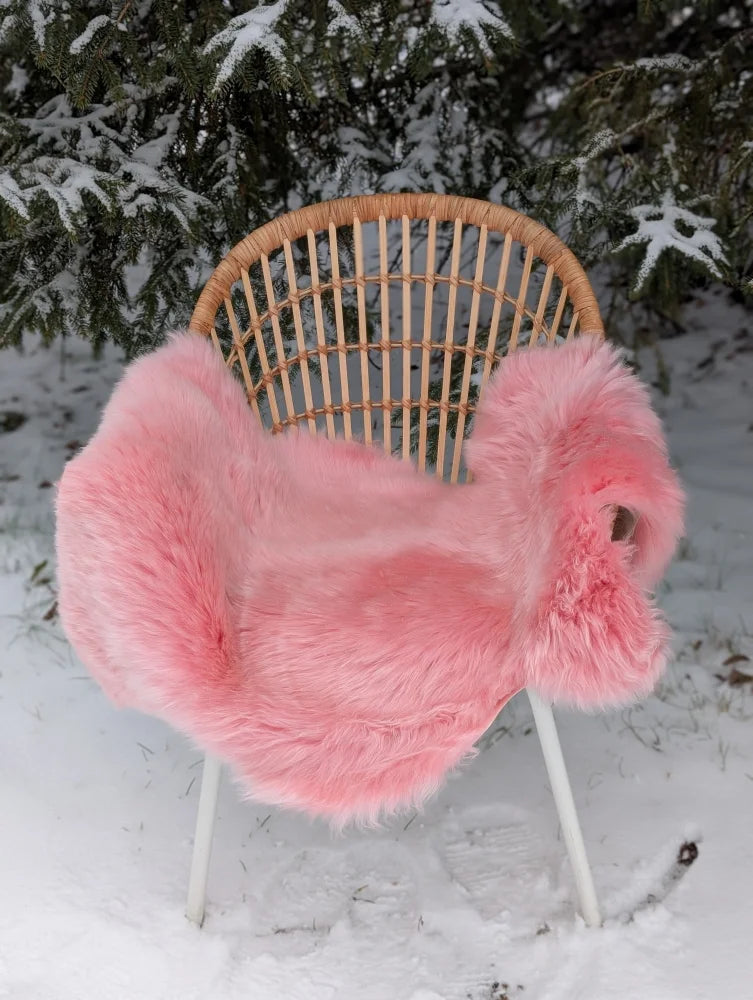 Pink merino sheepskin faux fur chair cover draped over wicker chair soft cozy vibe arriving mid october