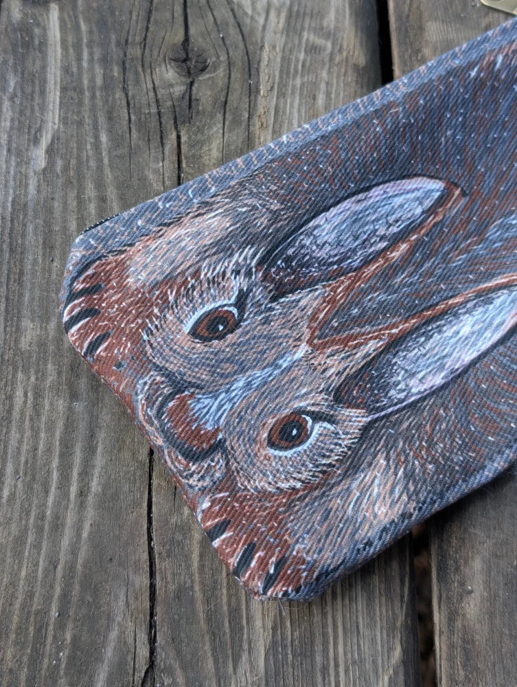 Rectangular cotton canvas coin purse with a detailed rabbit illustration and a fluffy sheepskin tail on dark background