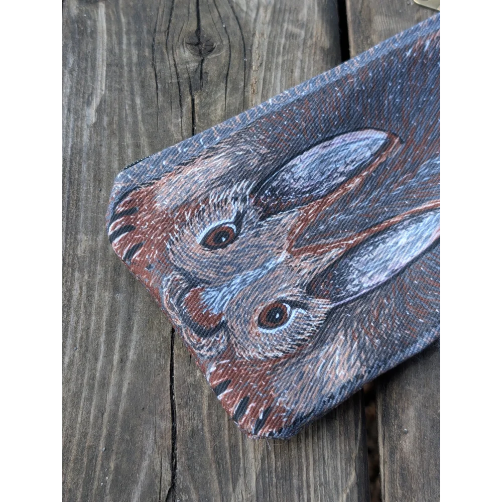 Rectangular cotton canvas coin purse with a detailed rabbit illustration and a fluffy sheepskin tail on dark background