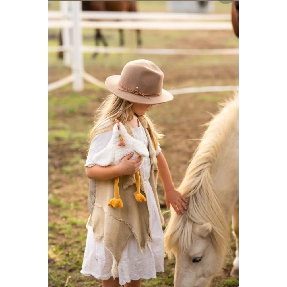 Charlie The Chicken beige white layered dress with brown hat yellow tassels Angus Oliver sheepskin rug
