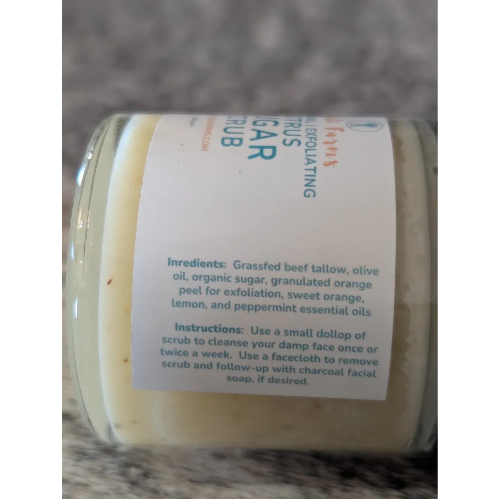 A clear glass jar of pale yellow tallow based citrus sugar scrub with orange peel and peppermint by angus oliver