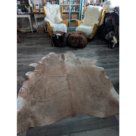 A large cowhide rug cow10 in natural tan and white with soft fluffy texture and unique characteristics for beautiful rugs
