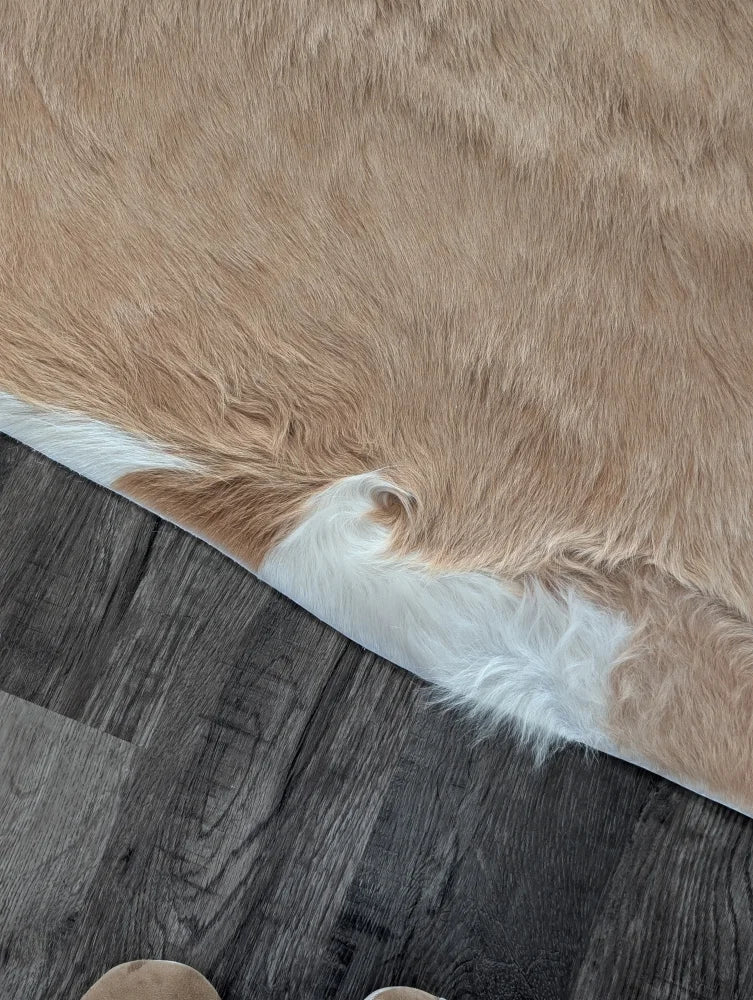 A large cowhide rug in tan and white with soft natural fur texture showcasing unique characteristics
