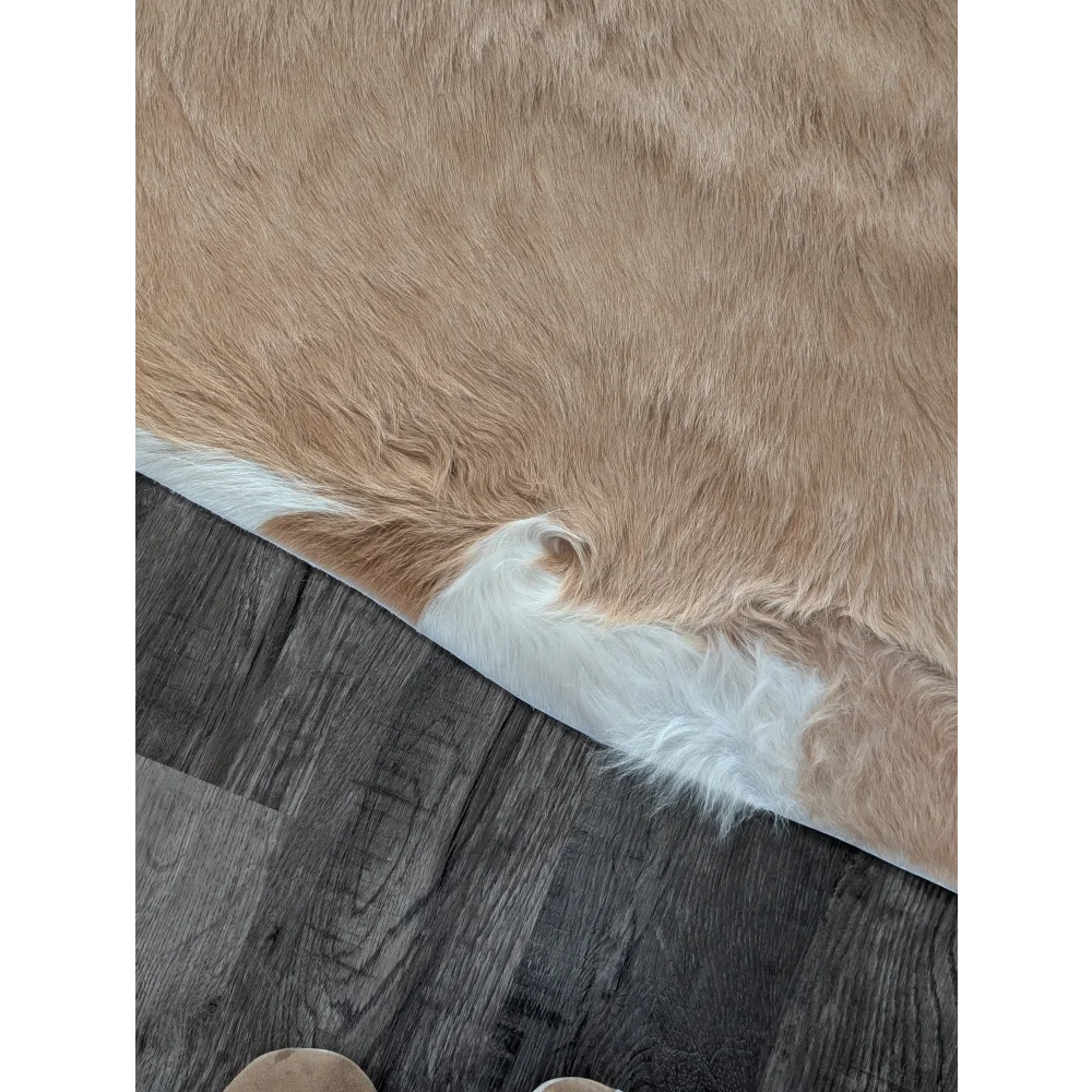 A large cowhide rug in tan and white with soft natural fur texture showcasing unique characteristics