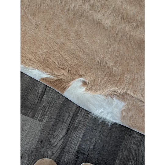 A large cowhide rug in tan and white with soft natural fur texture showcasing unique characteristics