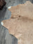 Large cowhide tan rug with white tipped edges and fluffy texture showing unique characteristics for beautiful rugs
