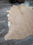 A large cowhide rug in tan and white with beautiful fluffy texture and unique characteristics for stylish decor