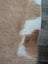 A large cowhide rug 82 by 77 inches with beautiful tan and white natural fur texture and unique characteristics