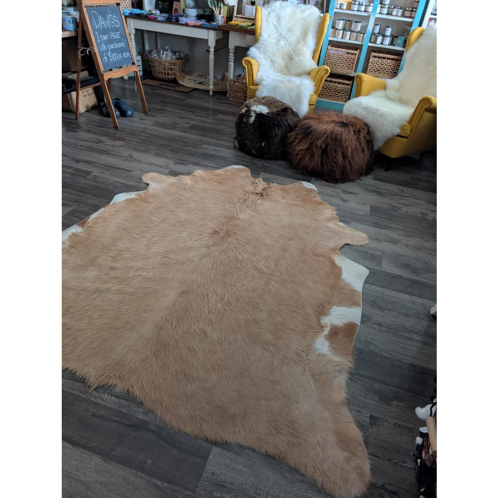 A large cowhide rug in natural tan and white with soft fluffy texture showcasing unique characteristics