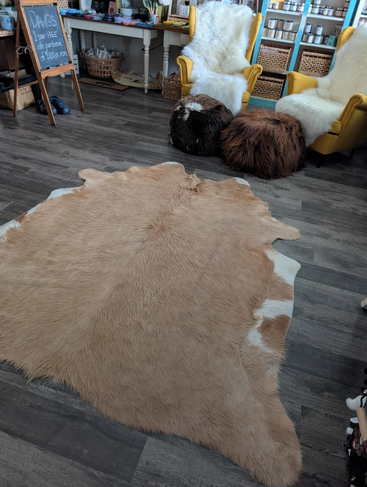 A large cowhide rug in natural tan and white with soft fluffy texture showcasing unique characteristics