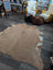 A large cowhide rug in natural tan and white with soft fluffy texture showcasing unique characteristics