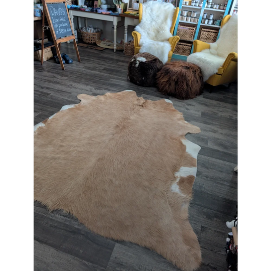 A large cowhide rug in natural tan and white with soft fluffy texture showcasing unique characteristics