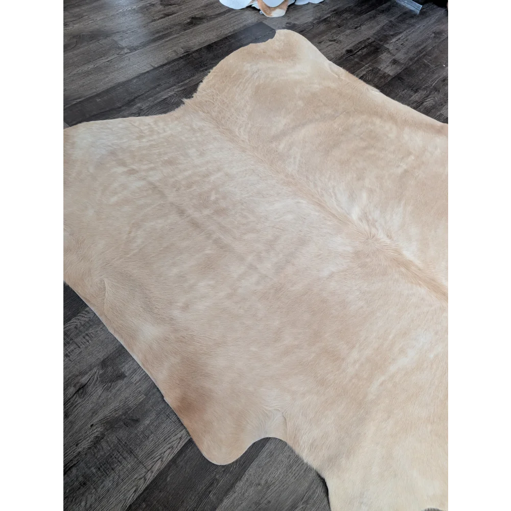 Beige large cowhide rug with natural fur texture and irregular edges showing unique characteristics