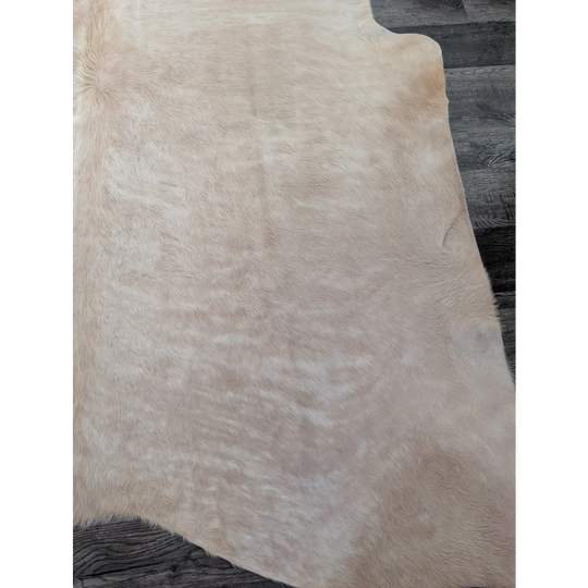 Cream-colored large cowhide rug with soft natural fur texture and unique irregular edges for beautiful rugs