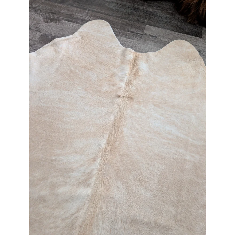 Cream-colored large cowhide rug with natural textured fur and central seam showcasing unique characteristics