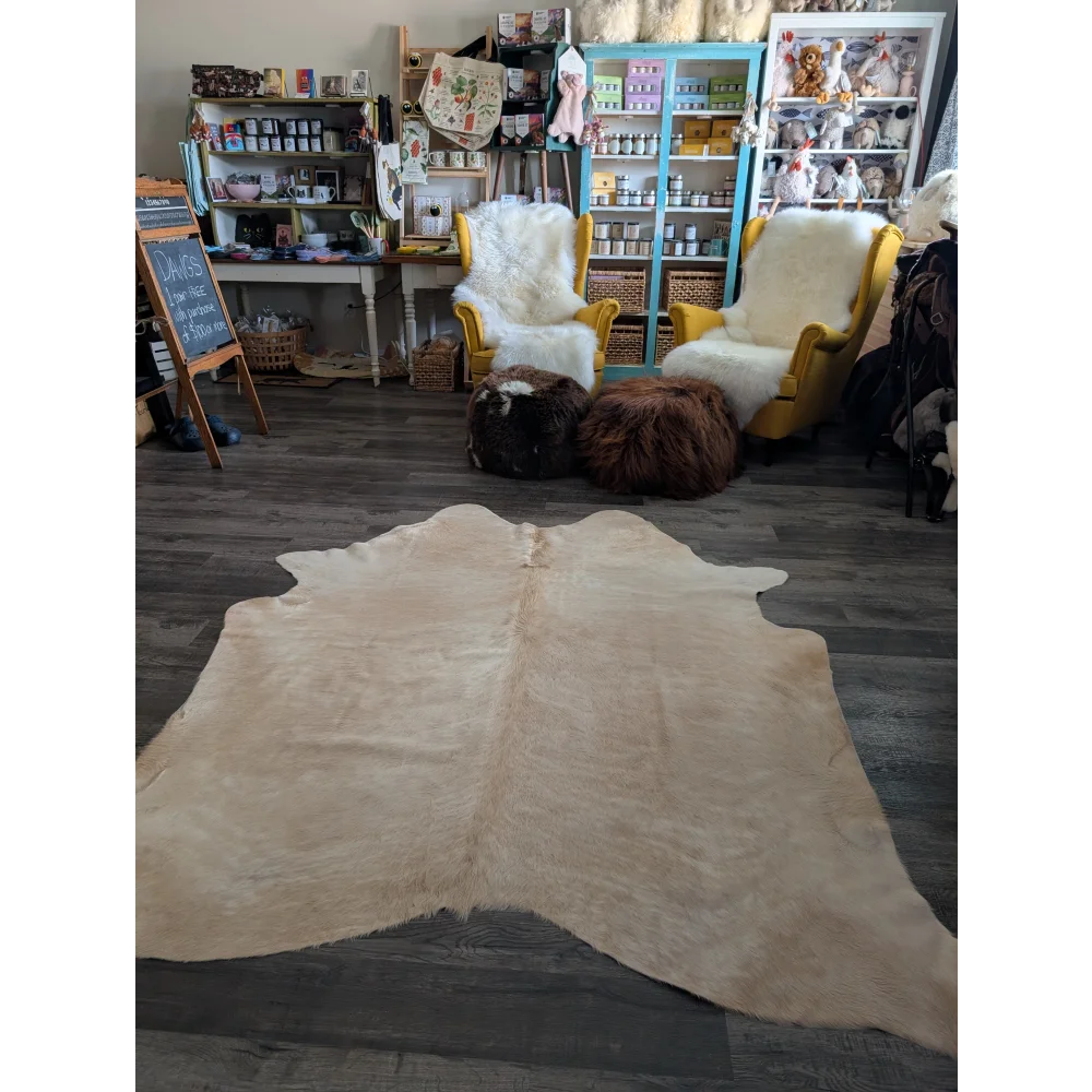 Beige large cowhide rug with natural textured surface and irregular edges perfect for beautiful rugs with unique characteristics