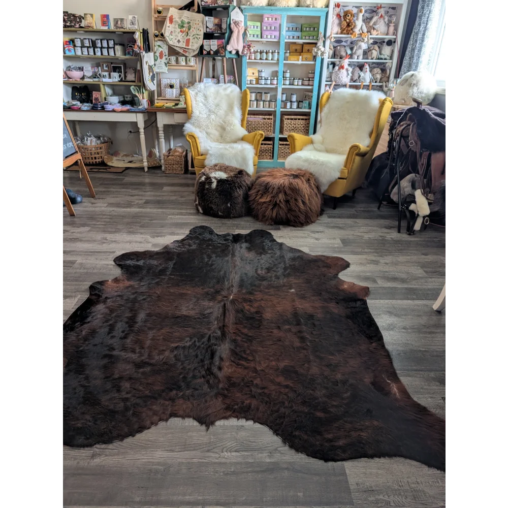Large cowhide rug with dark brown textured hide and black patches showcasing unique characteristics for beautiful rugs
