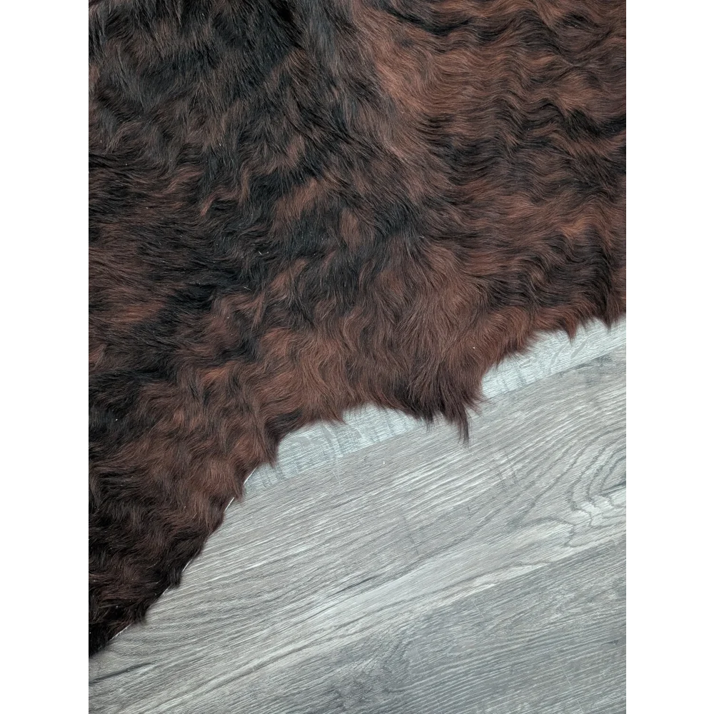 A large cowhide rug with beautiful dark brown and black fur showcasing unique characteristics and natural texture
